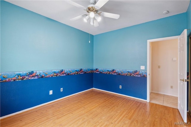 spare room featuring a ceiling fan, baseboards, and wood finished floors