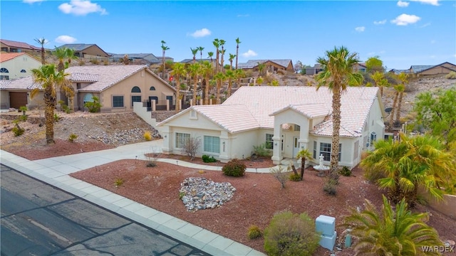 view of front of property with concrete driveway, a tile roof, a residential view, and stucco siding