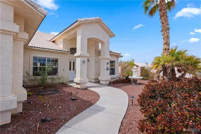 exterior space featuring a tile roof and stucco siding