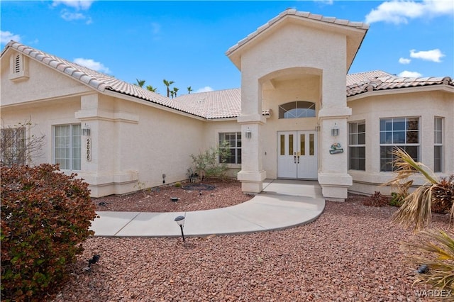 view of front of house featuring french doors, a tile roof, and stucco siding