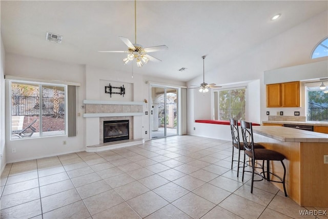 kitchen with a breakfast bar area, light tile patterned flooring, visible vents, open floor plan, and vaulted ceiling