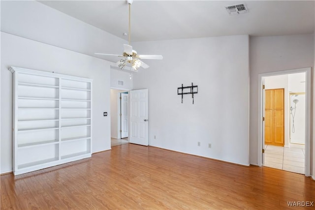 empty room with ceiling fan, wood finished floors, and visible vents