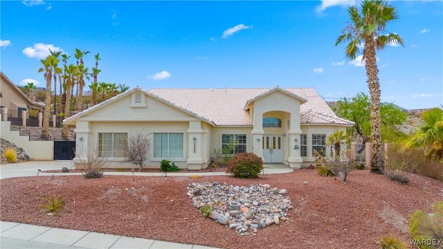 view of front of home with a tiled roof, fence, and stucco siding