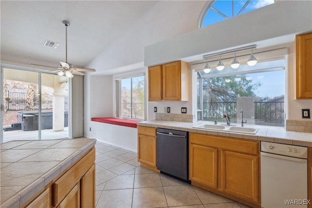 kitchen featuring tile countertops, a sink, visible vents, black dishwasher, and vaulted ceiling