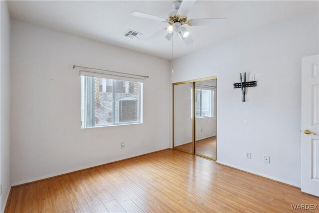 unfurnished bedroom with light wood-style flooring, a closet, visible vents, and a ceiling fan