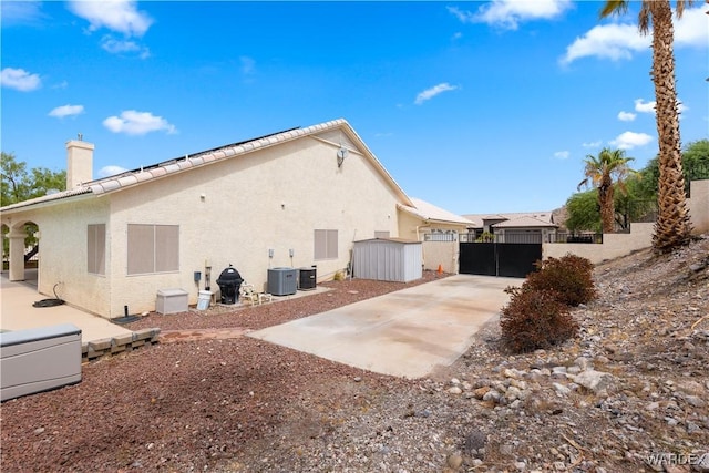 back of house with a chimney, fence, a patio, and stucco siding