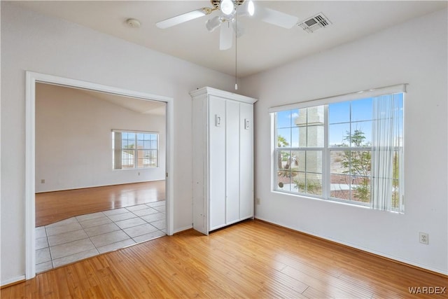 unfurnished bedroom with light wood-style floors, visible vents, and a ceiling fan