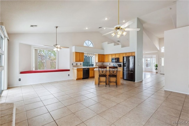 kitchen featuring black appliances, ceiling fan, a kitchen island, and light countertops