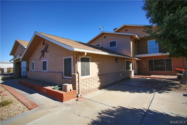 view of front of property featuring brick siding, a patio area, and stucco siding