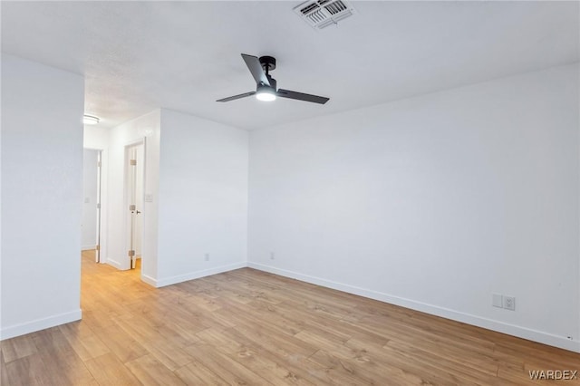 empty room featuring a ceiling fan, light wood-type flooring, visible vents, and baseboards