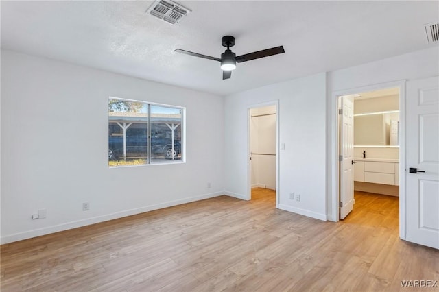 unfurnished bedroom with light wood-type flooring, visible vents, a spacious closet, and baseboards