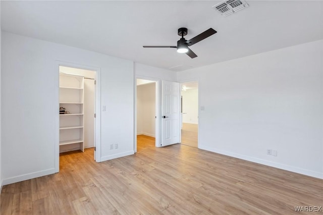 unfurnished bedroom with baseboards, visible vents, a spacious closet, light wood-type flooring, and a closet