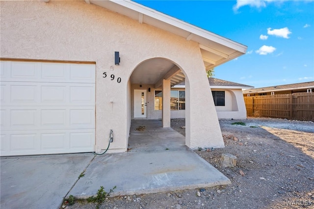 view of exterior entry featuring an attached garage and stucco siding