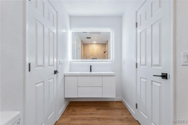 bathroom featuring toilet, baseboards, wood finished floors, and vanity