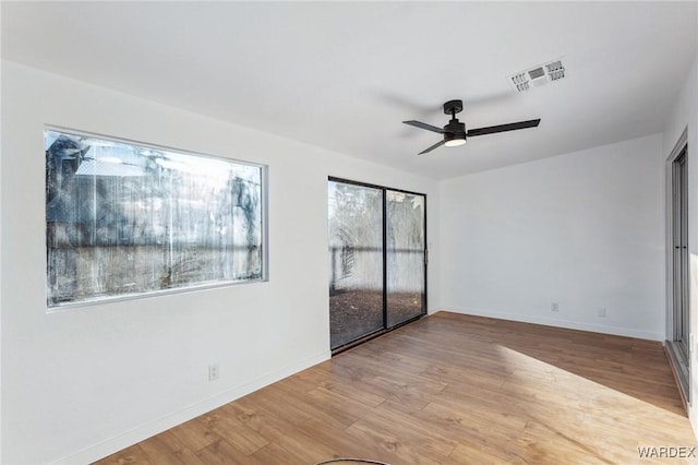 unfurnished room featuring light wood finished floors, baseboards, visible vents, and a ceiling fan