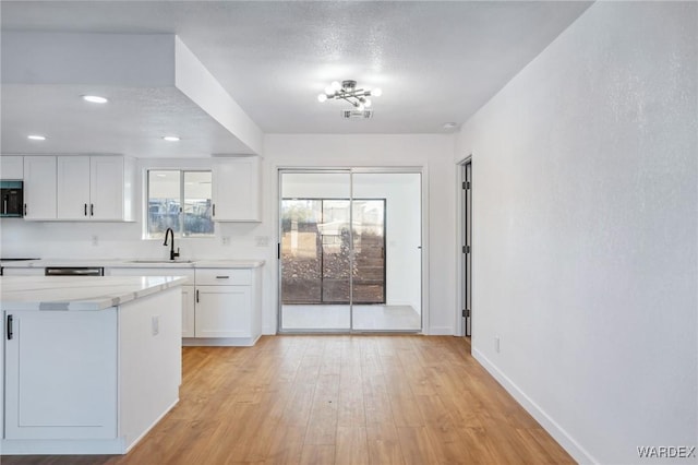 kitchen featuring white cabinets, visible vents, black microwave, and light countertops