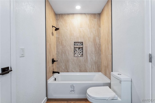 bathroom featuring  shower combination, a textured wall, and toilet