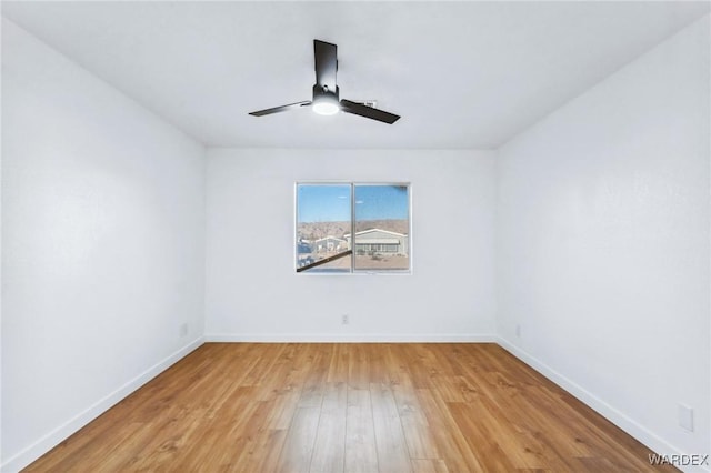 empty room with baseboards, ceiling fan, and light wood-style floors