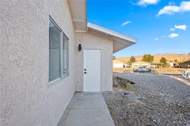 view of exterior entry with a mountain view and stucco siding