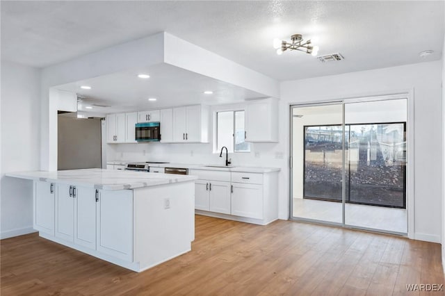 kitchen with stainless steel appliances, a sink, visible vents, white cabinetry, and light wood-style floors