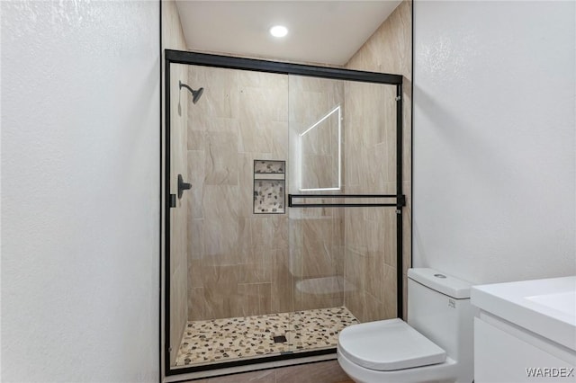 bathroom featuring vanity, a shower stall, and toilet