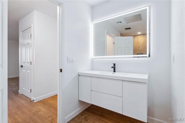 bathroom with visible vents, wood finished floors, vanity, and baseboards