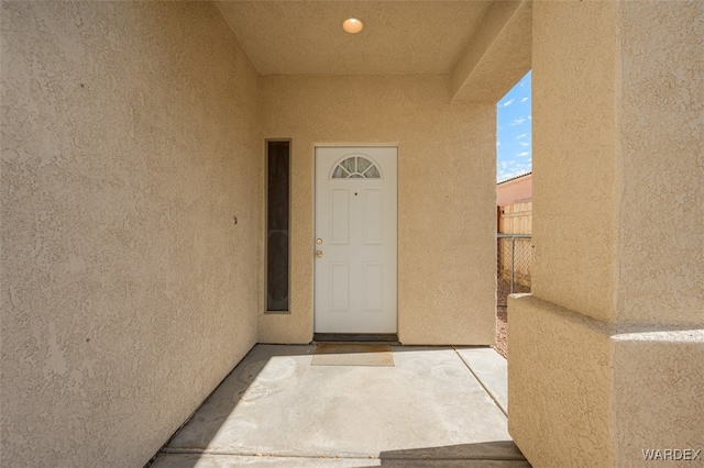 entrance to property with fence and stucco siding