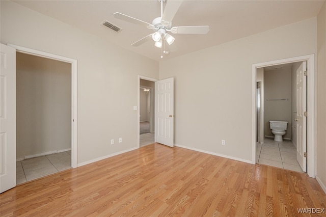 unfurnished bedroom featuring ceiling fan, connected bathroom, visible vents, baseboards, and light wood-style floors