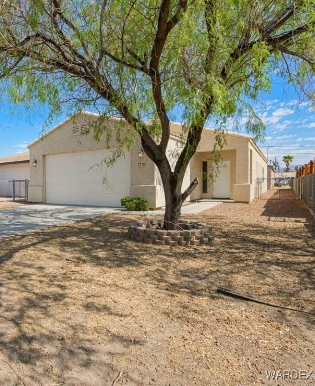 view of front facade featuring concrete driveway, fence, an attached garage, and stucco siding