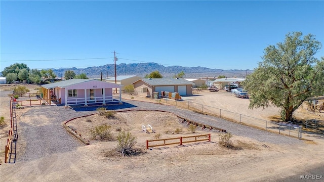 view of front of home with dirt driveway, covered porch, fence, and a mountain view