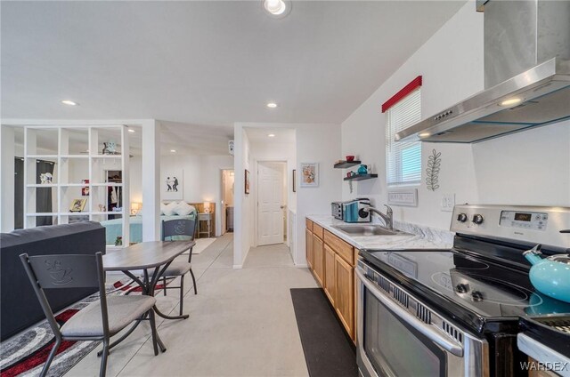 kitchen featuring recessed lighting, a sink, light countertops, wall chimney exhaust hood, and stainless steel range with electric stovetop