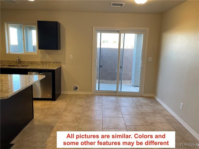 kitchen with visible vents, light stone countertops, dark cabinetry, stainless steel dishwasher, and a sink