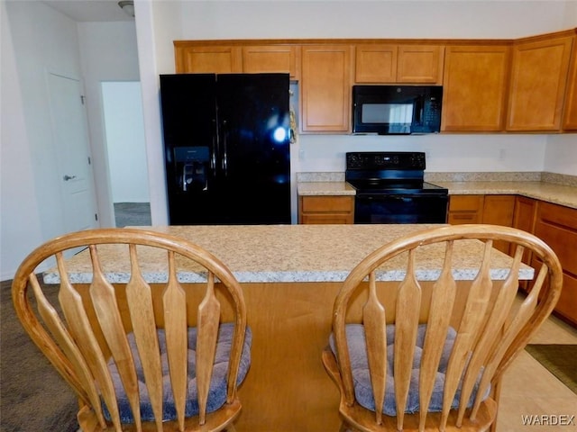 kitchen featuring black appliances, brown cabinetry, and light countertops