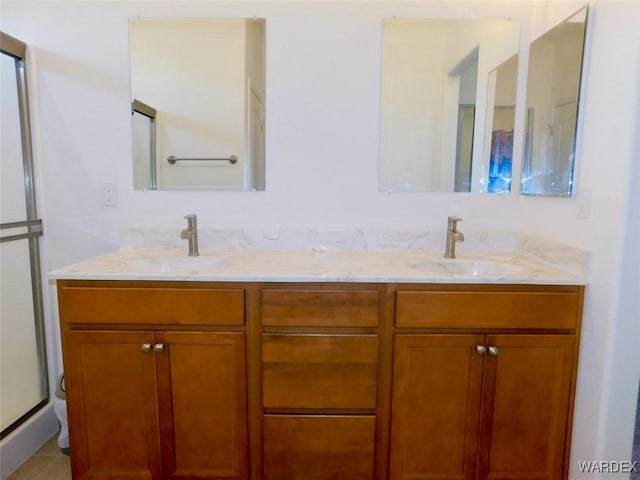 bathroom featuring double vanity, a shower stall, and a sink