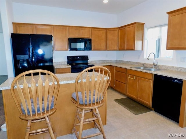 kitchen featuring black appliances, a kitchen island, a sink, and brown cabinetry