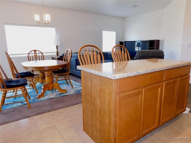 kitchen with light stone counters, a kitchen island, open floor plan, brown cabinetry, and decorative light fixtures