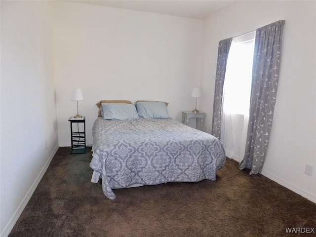 bedroom featuring dark carpet and baseboards