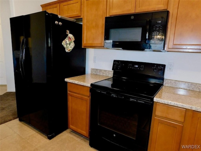 kitchen with black appliances, light tile patterned floors, light stone counters, and brown cabinetry