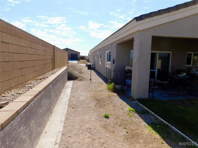 view of side of home with a patio area, a fenced backyard, and stucco siding