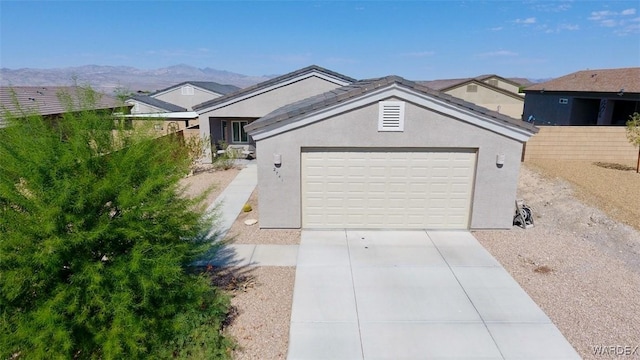 single story home featuring stucco siding, an attached garage, fence, a mountain view, and driveway