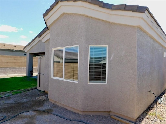 view of property exterior with fence and stucco siding