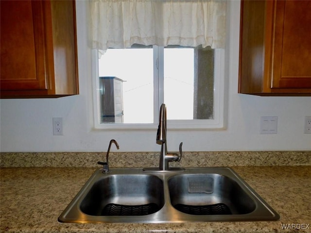 kitchen with brown cabinetry, light countertops, and a sink