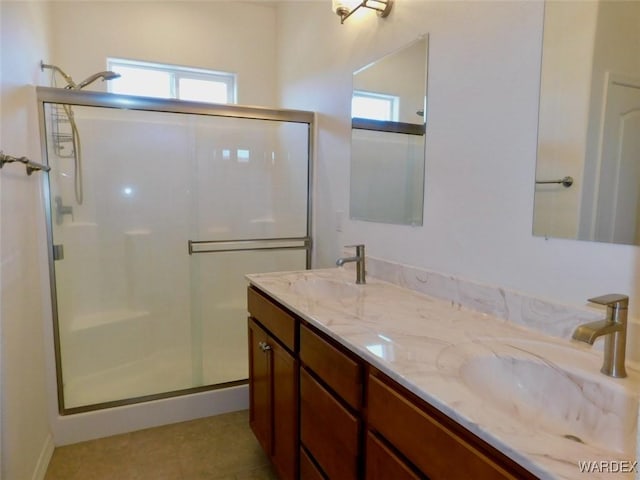 full bathroom with double vanity, a stall shower, a sink, and tile patterned floors