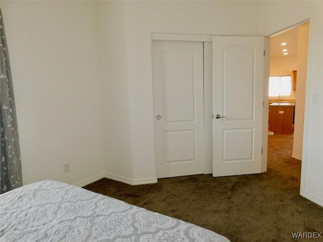 unfurnished bedroom featuring a closet, dark carpet, and baseboards