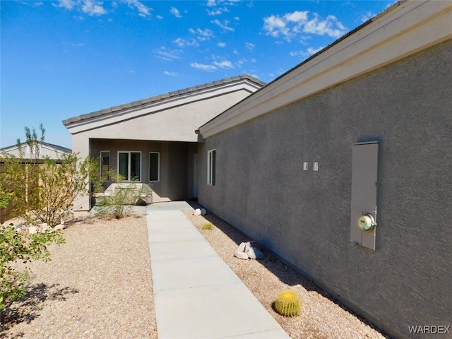 property entrance with a patio area, fence, and stucco siding