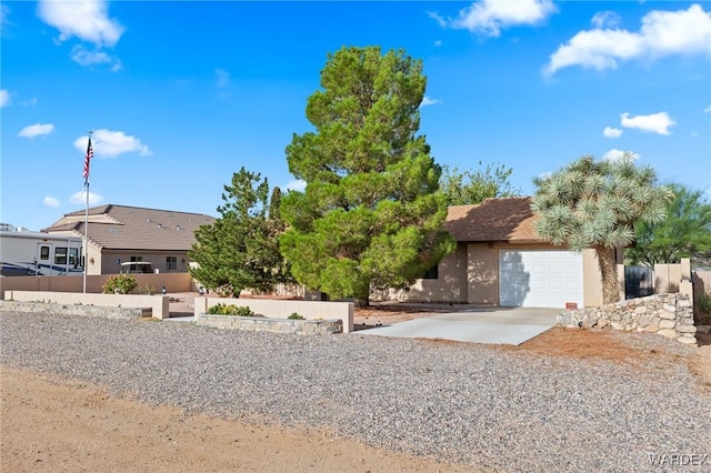 ranch-style house with a garage, concrete driveway, fence, and stucco siding