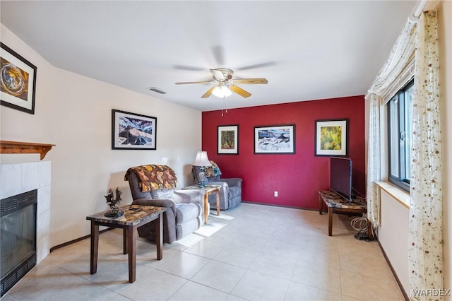 living area featuring visible vents, baseboards, ceiling fan, an accent wall, and a fireplace