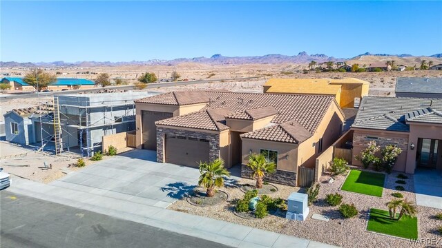 view of front of home with a tile roof, stucco siding, a mountain view, a garage, and stone siding