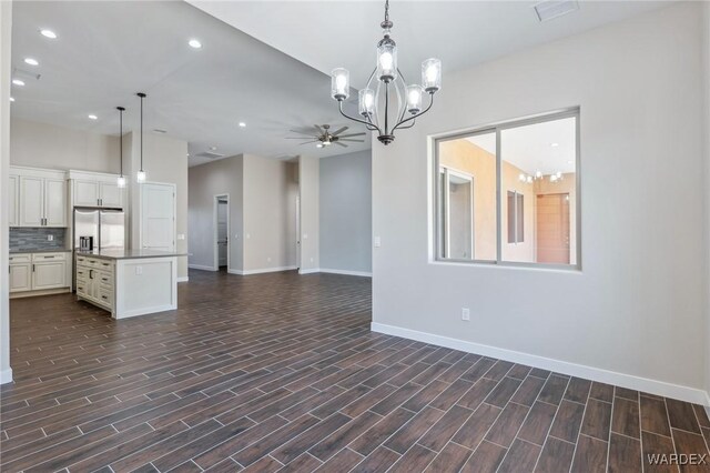 unfurnished living room featuring ceiling fan with notable chandelier, baseboards, dark wood finished floors, and recessed lighting