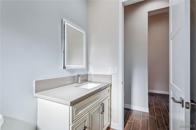 bathroom featuring wood finish floors, vanity, and baseboards